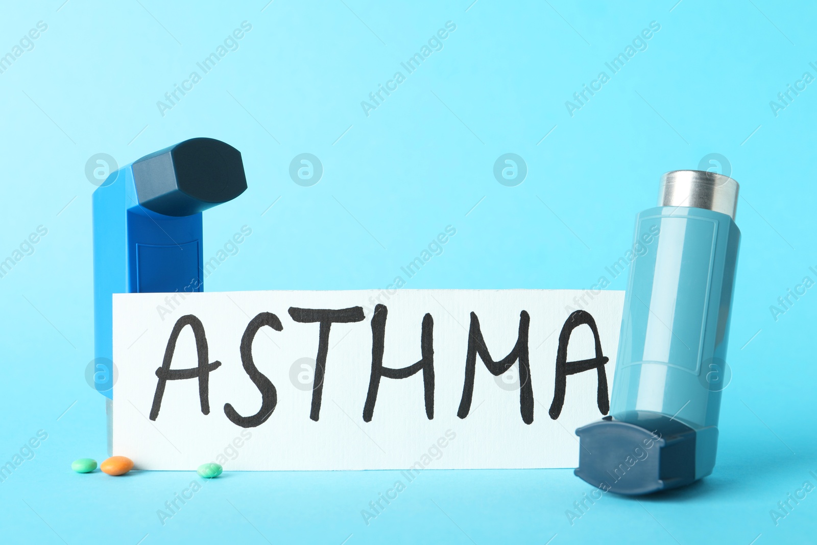 Photo of Card with word Asthma and inhalers on light blue background, closeup