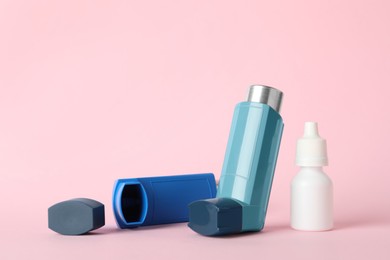 Photo of Inhalers and medical drops on pink background, closeup. Asthma treatment