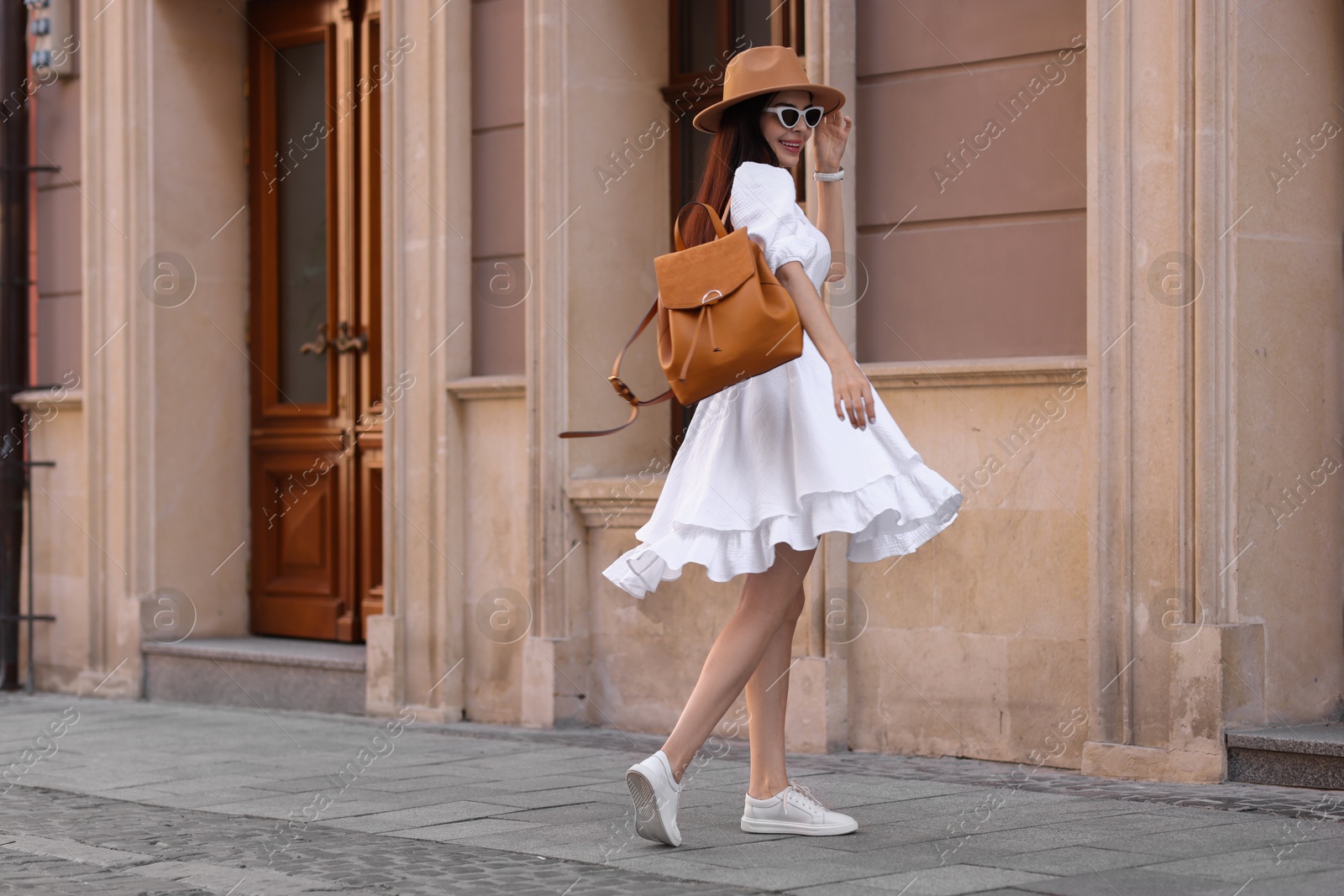 Photo of Smiling woman in stylish hat and sunglasses on city street