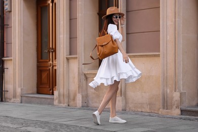 Smiling woman in stylish hat and sunglasses on city street