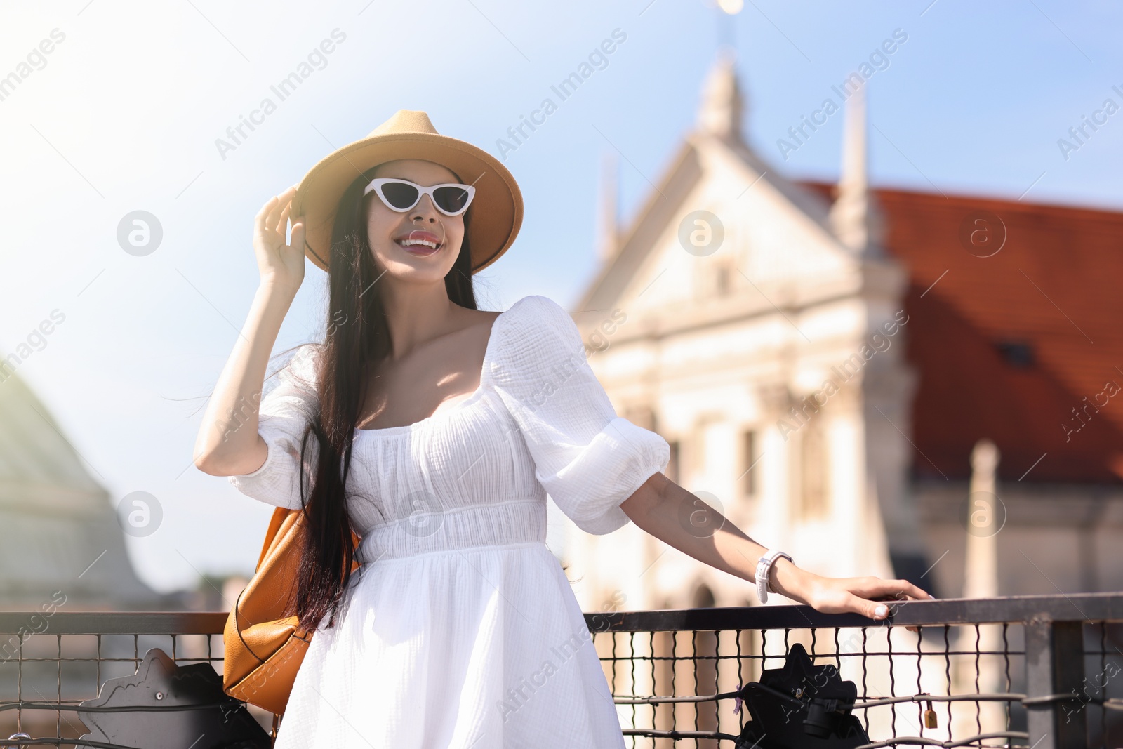 Photo of Smiling woman in stylish hat and sunglasses with backpack on city street