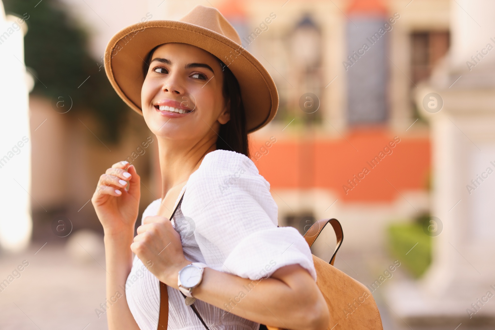 Photo of Beautiful young woman in stylish hat with backpack outdoors