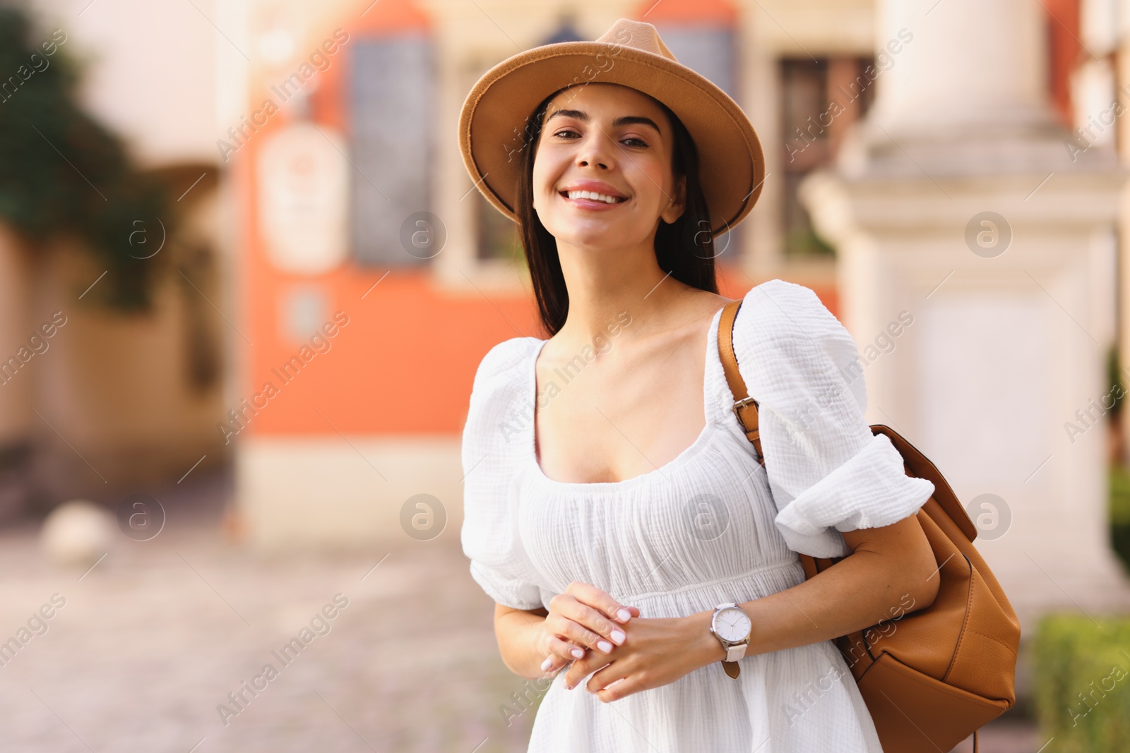 Photo of Beautiful young woman in stylish hat with backpack outdoors, space for text