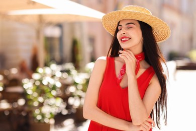 Beautiful young woman in stylish hat on city street. Space for text