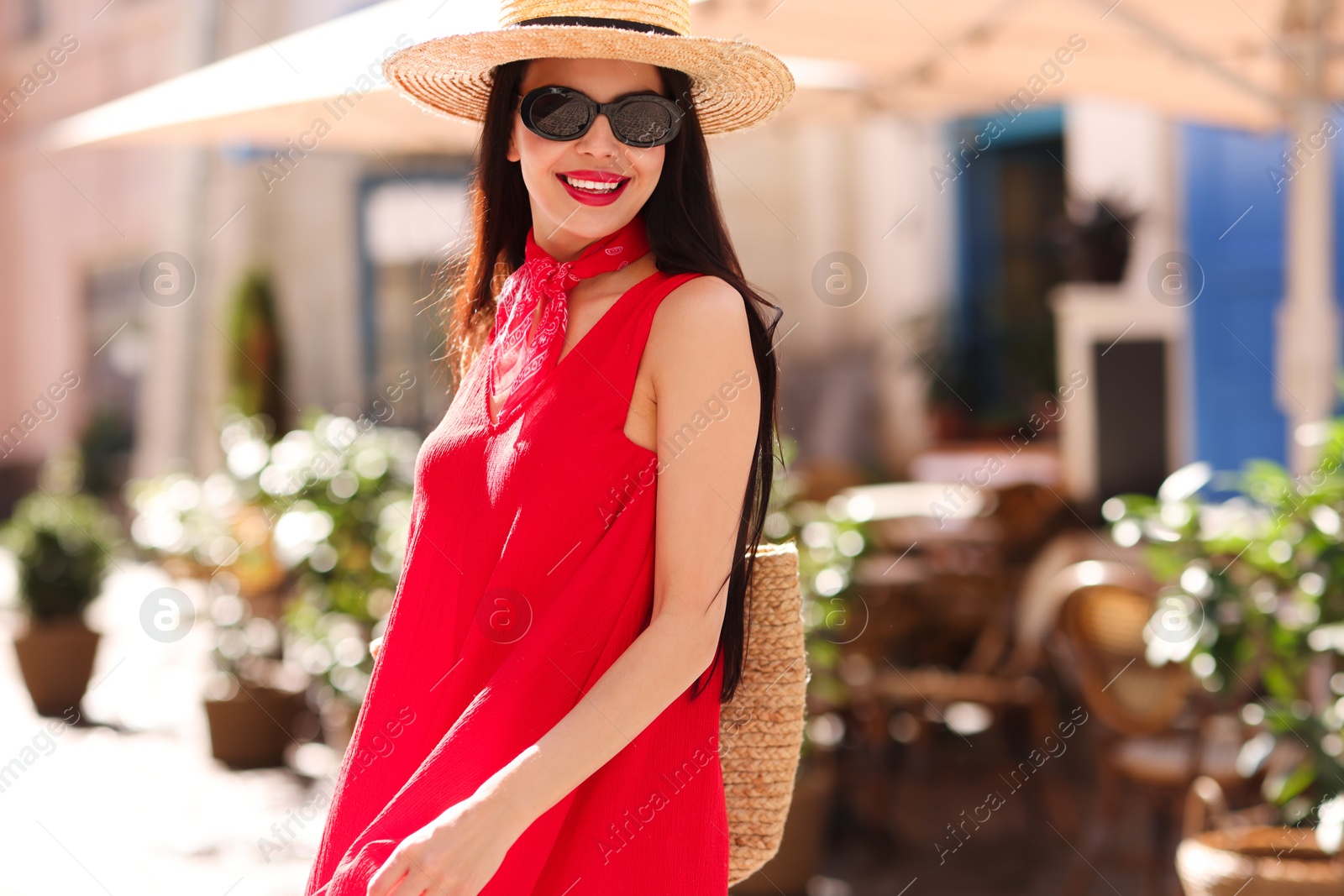 Photo of Smiling young woman in stylish hat and sunglasses on city street