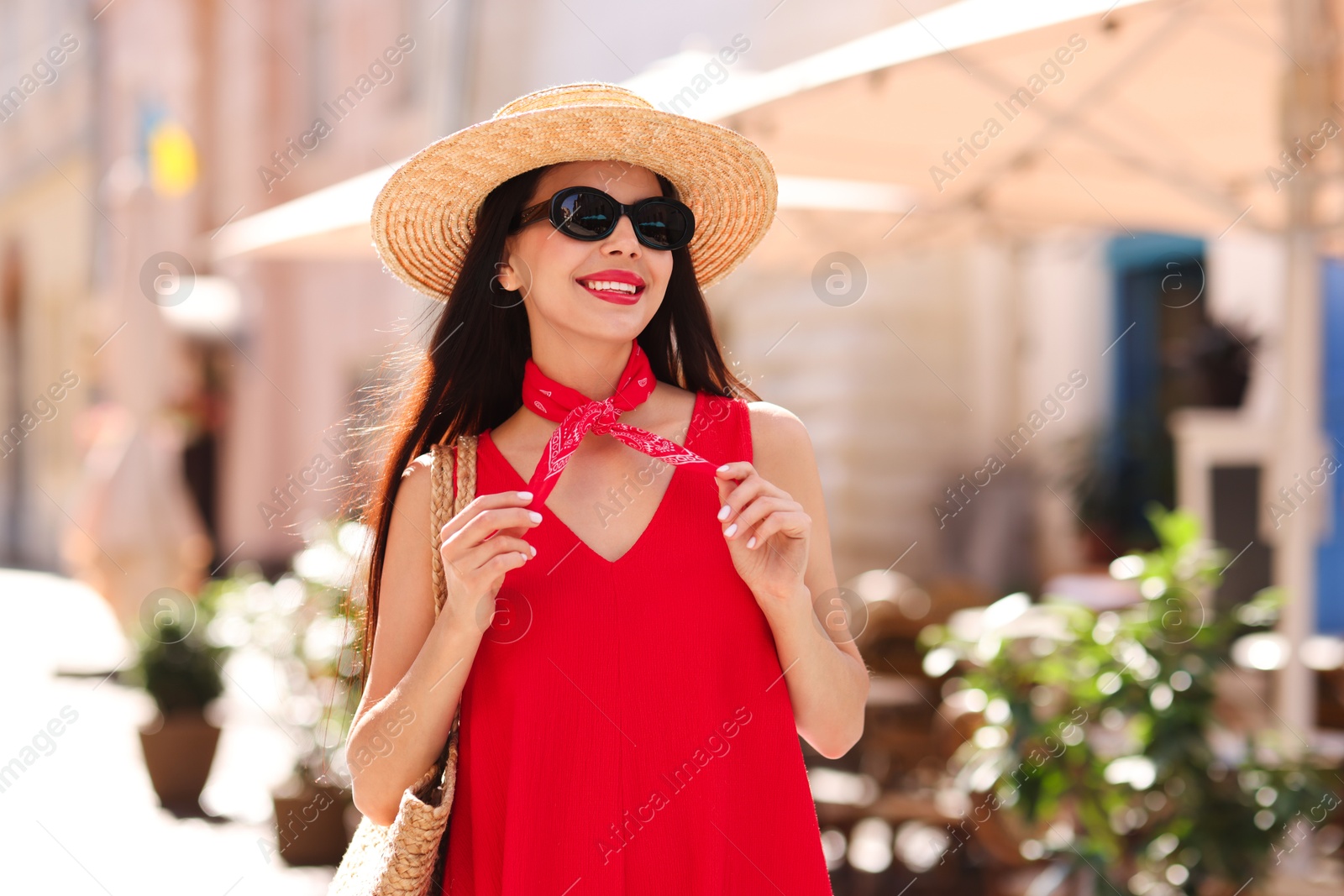 Photo of Smiling young woman in stylish hat and sunglasses on city street