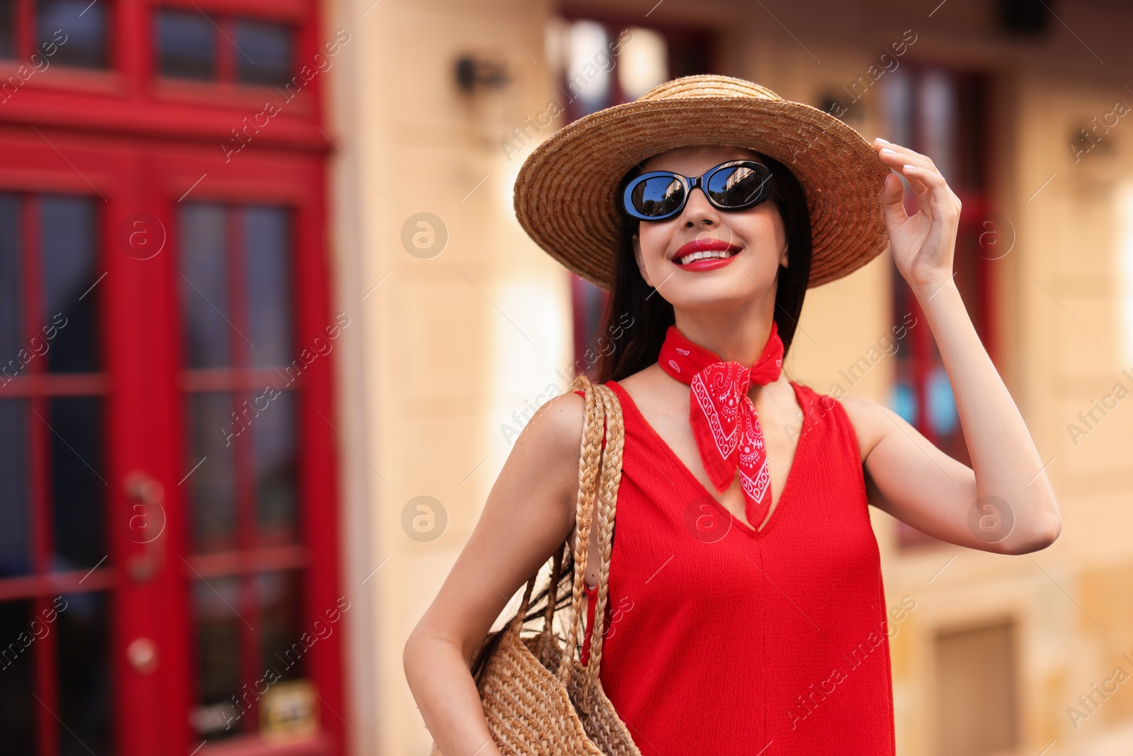 Photo of Smiling young woman in stylish hat and sunglasses on city street