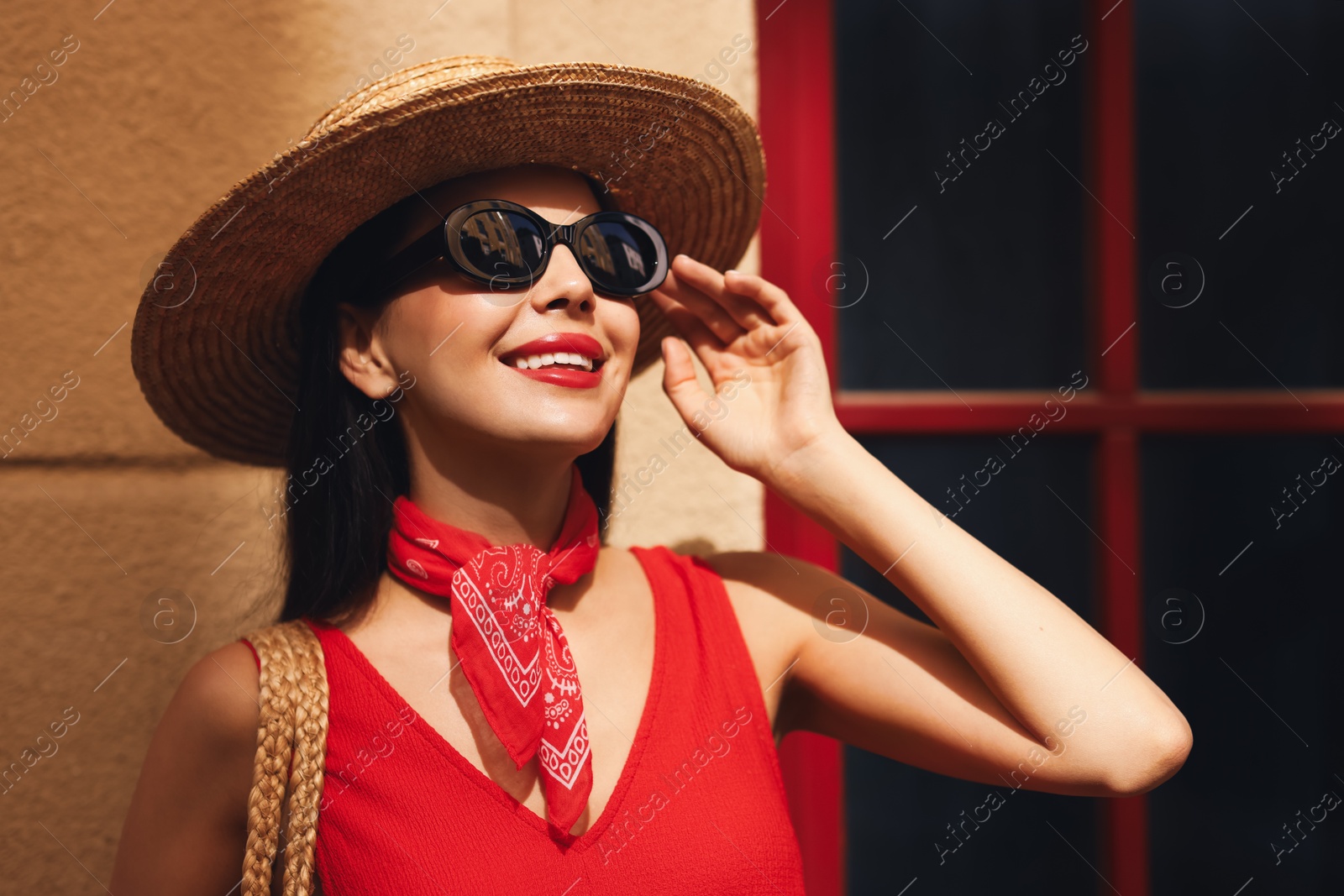 Photo of Smiling young woman in stylish hat and sunglasses near building outdoors