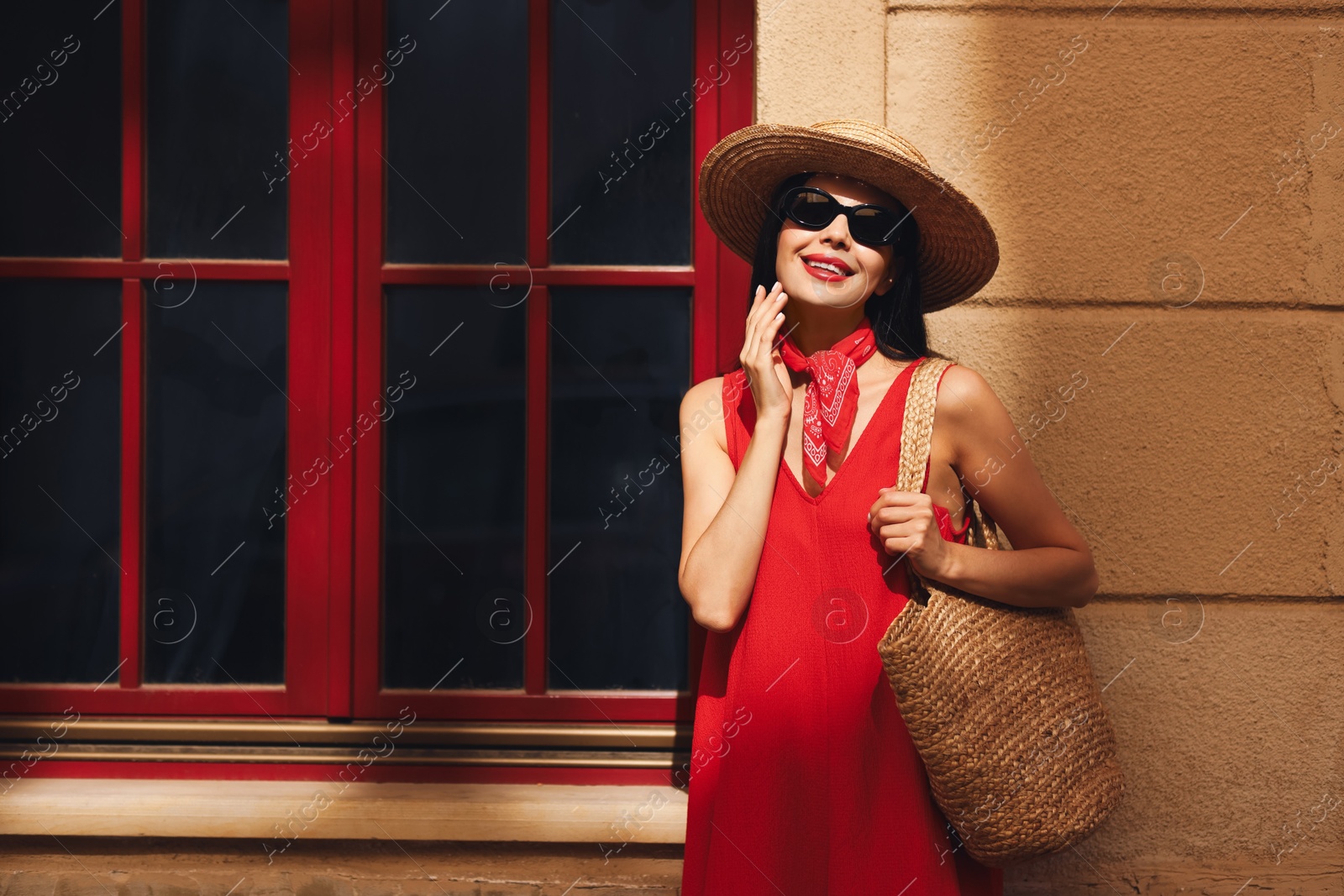 Photo of Smiling young woman in stylish hat and sunglasses near building outdoors