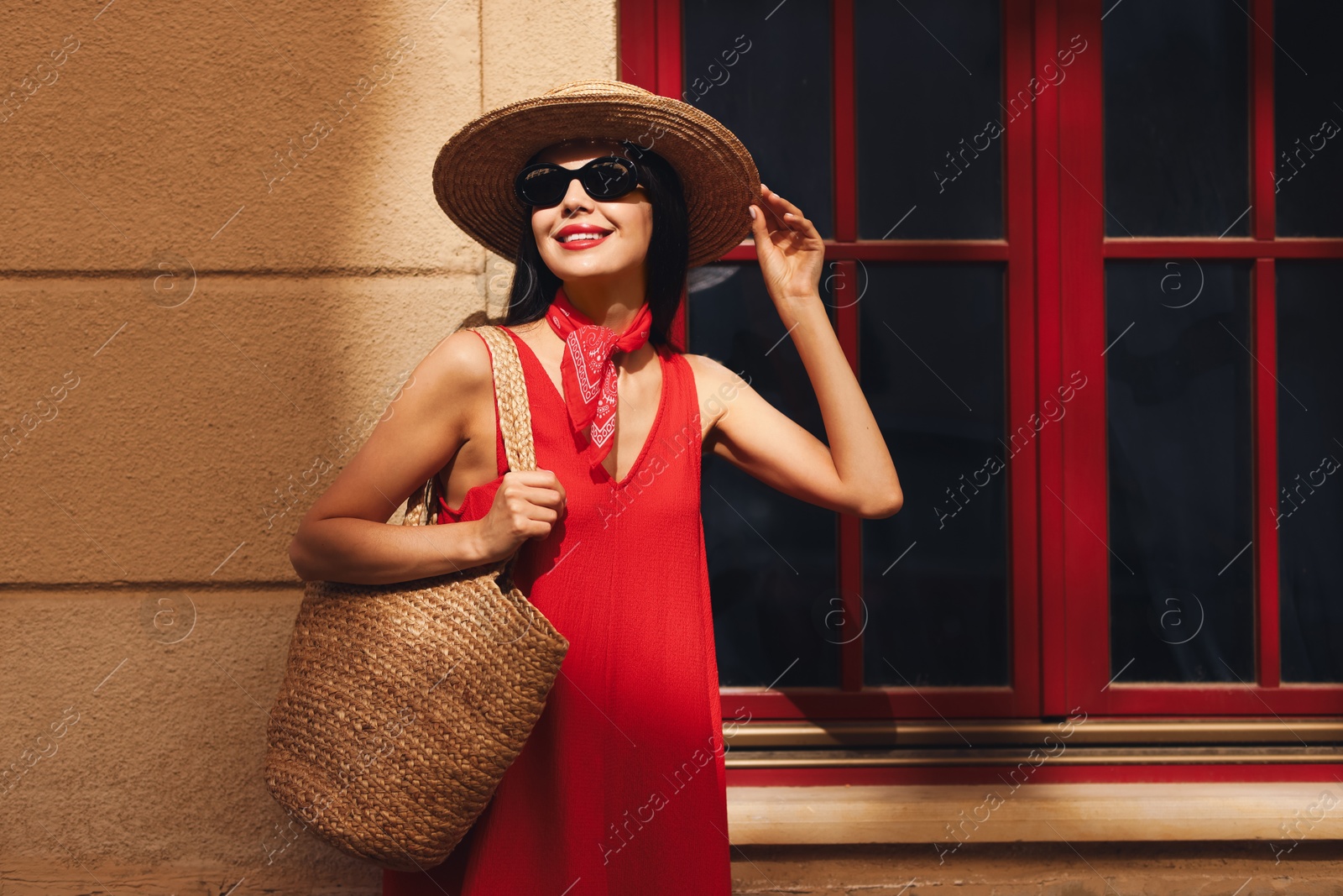 Photo of Smiling young woman in stylish hat and sunglasses near building outdoors