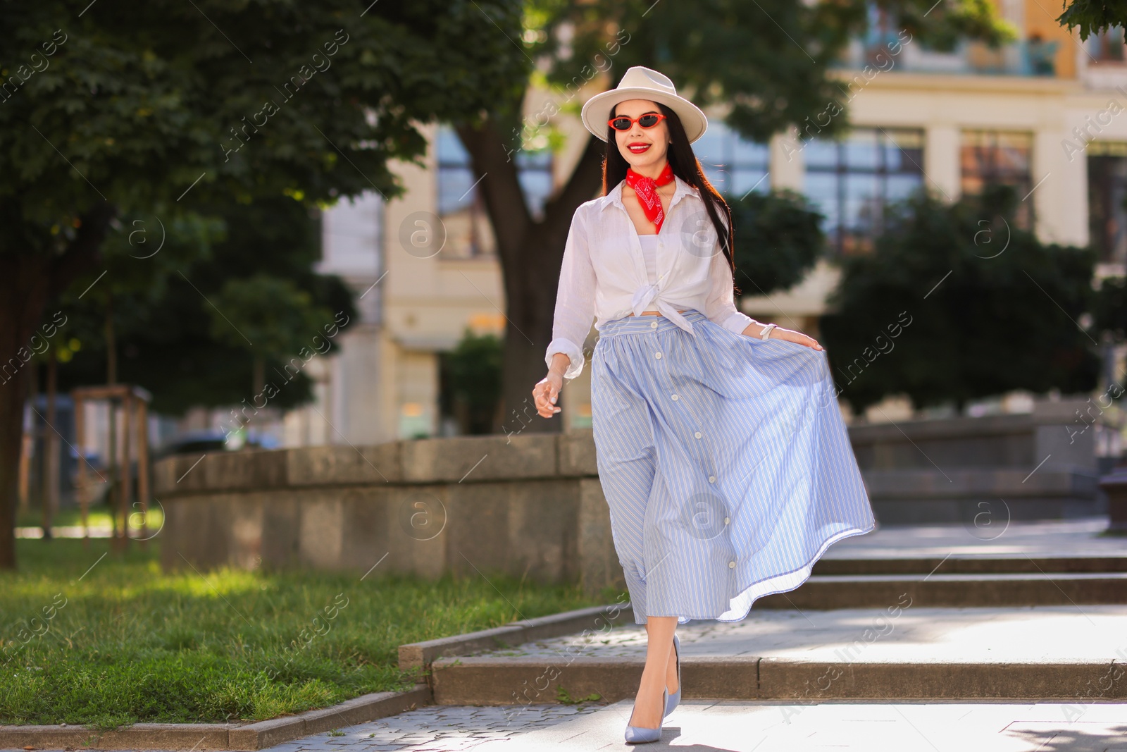 Photo of Smiling young woman in stylish hat and sunglasses on city street