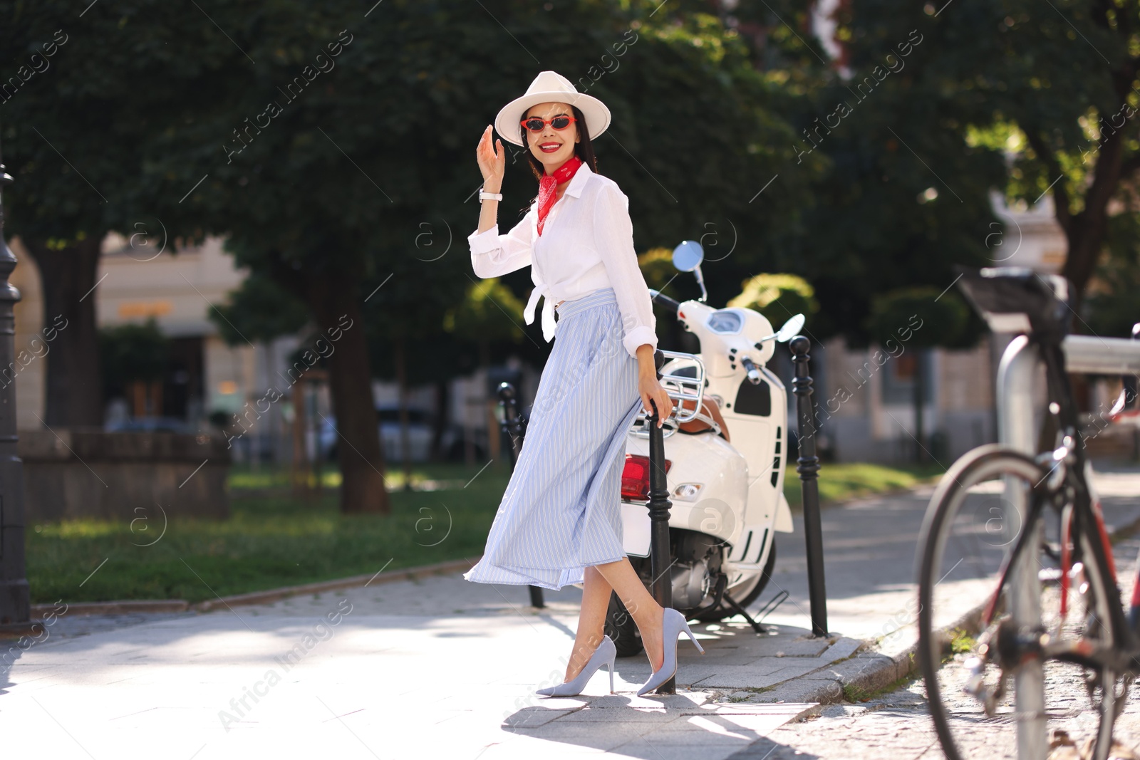 Photo of Smiling young woman in stylish hat and sunglasses on city street