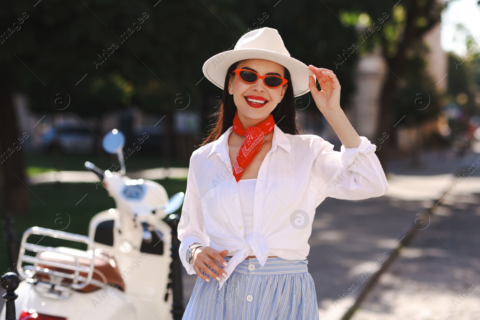 Photo of Smiling young woman in stylish hat and sunglasses on city street