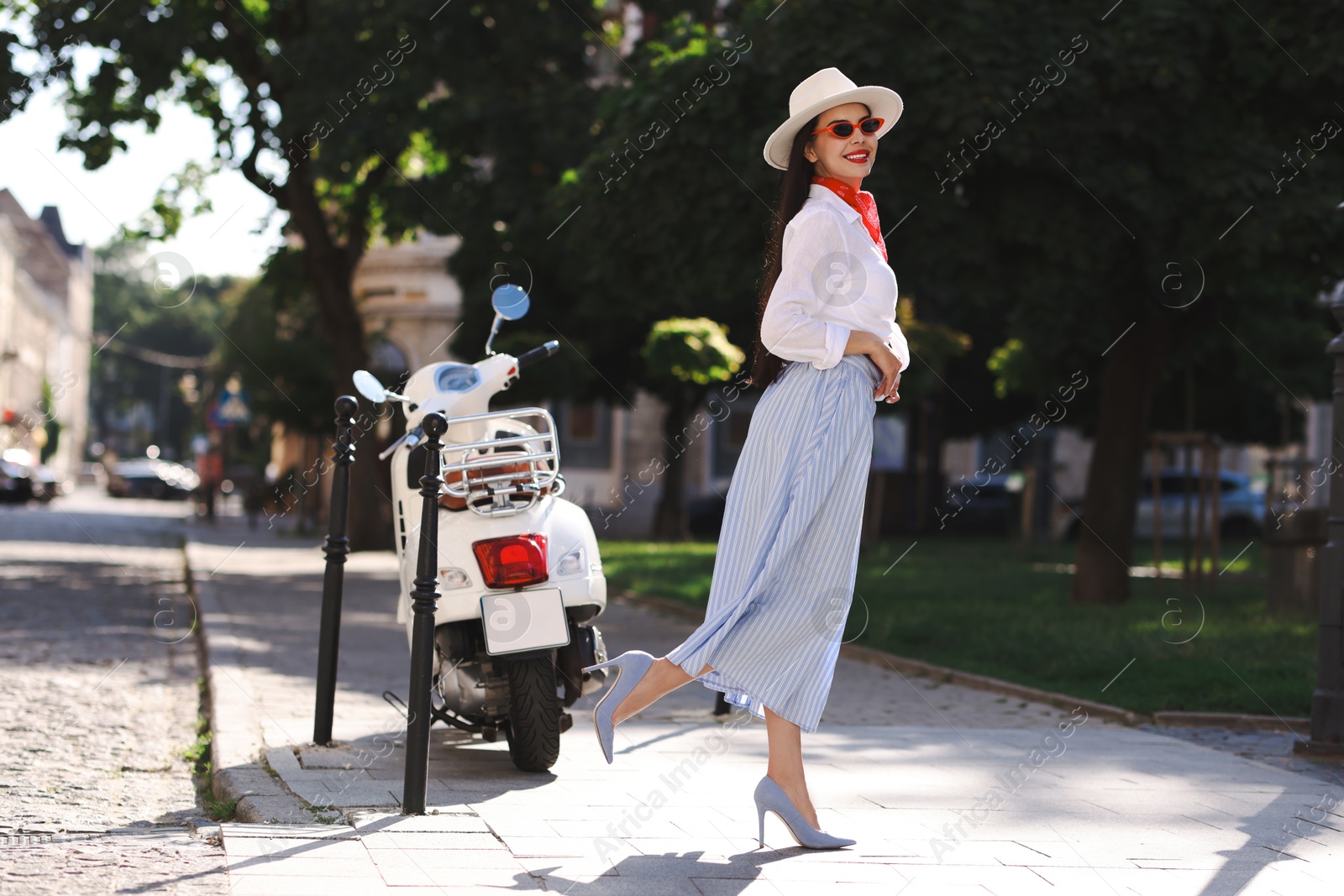 Photo of Smiling young woman in stylish hat and sunglasses on city street