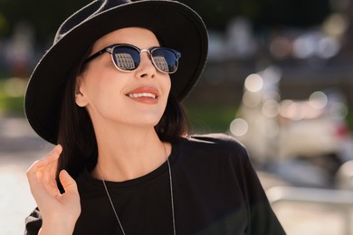 Smiling woman in stylish black hat and sunglasses outdoors