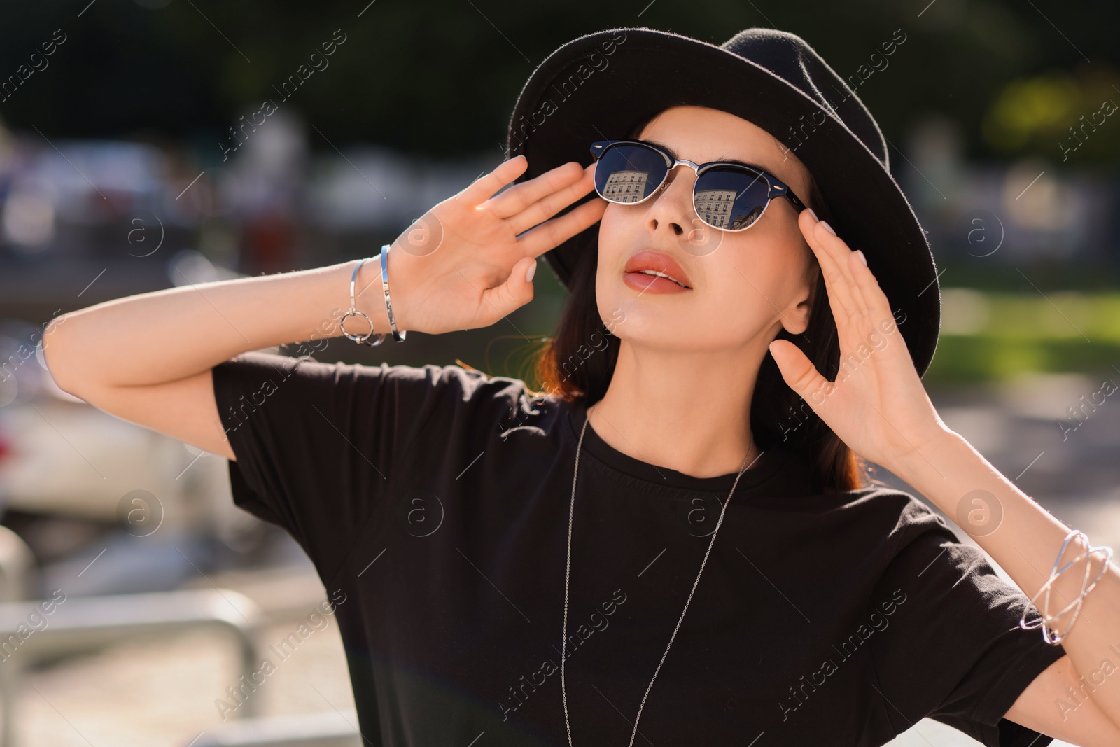 Photo of Young woman in stylish black hat and sunglasses outdoors