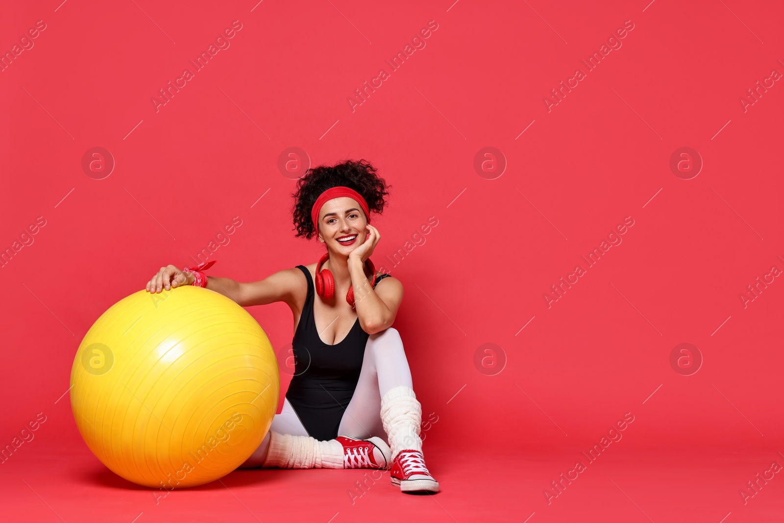 Photo of Aerobics. Happy woman with fitness ball on red background, space for text