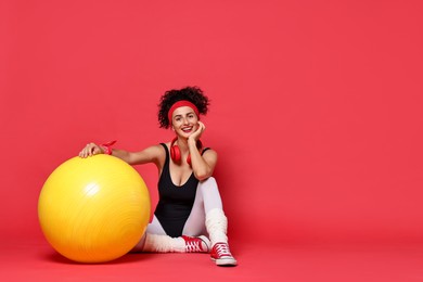 Aerobics. Happy woman with fitness ball on red background, space for text