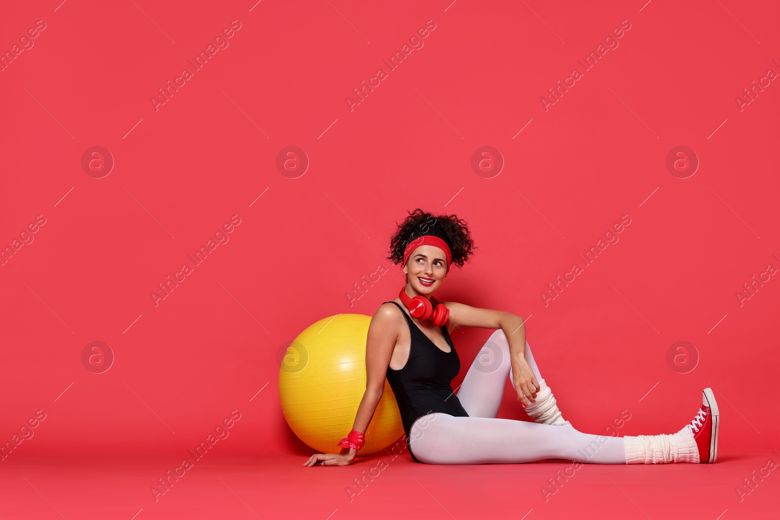 Photo of Aerobics. Happy woman with fitness ball on red background