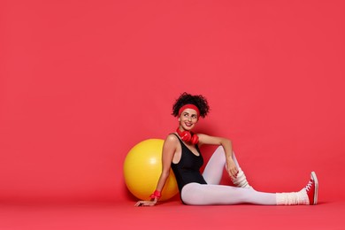 Aerobics. Happy woman with fitness ball on red background