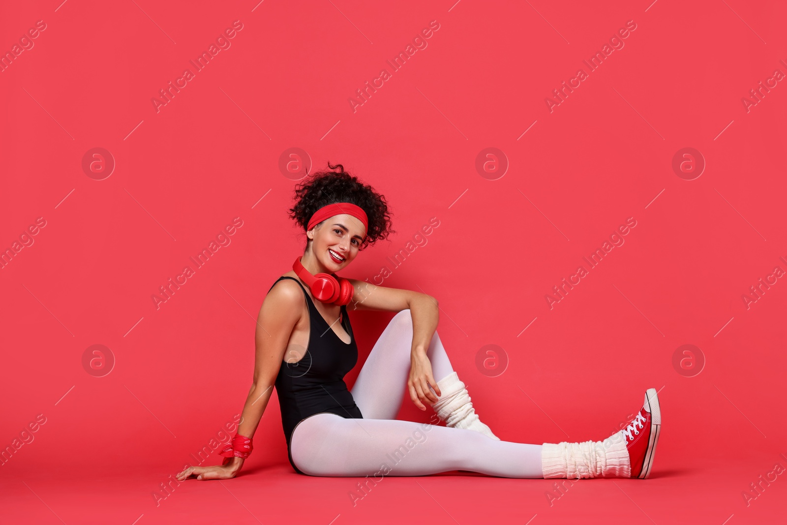 Photo of Aerobics. Happy woman with headphones on red background