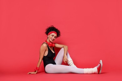 Aerobics. Happy woman with headphones on red background