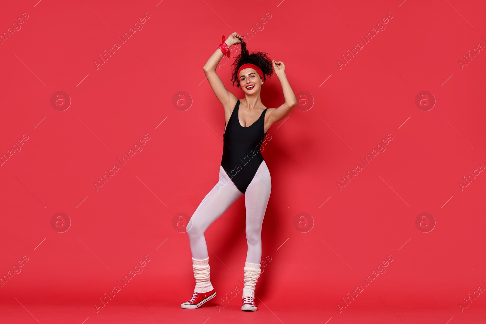 Photo of Aerobics. Happy woman in sportswear on red background