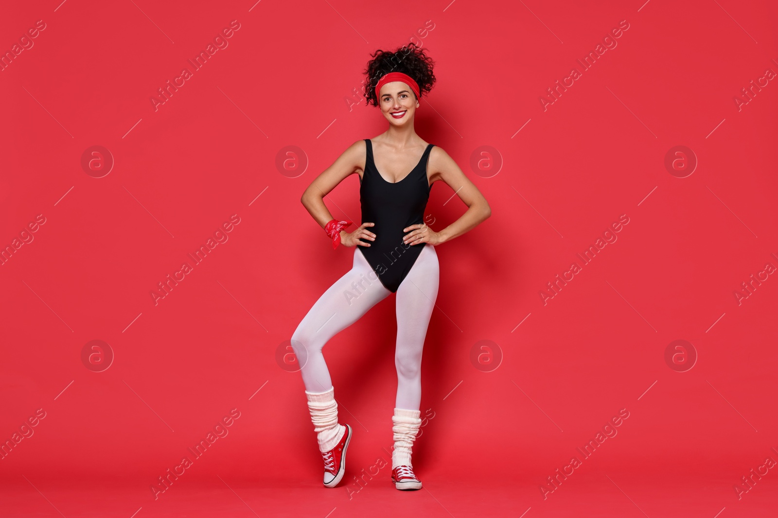 Photo of Aerobics. Happy woman in sportswear on red background