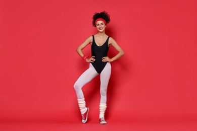 Photo of Aerobics. Happy woman in sportswear on red background