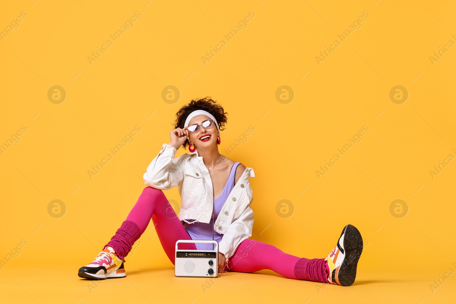 Photo of Aerobics. Woman with radio receiver on orange background