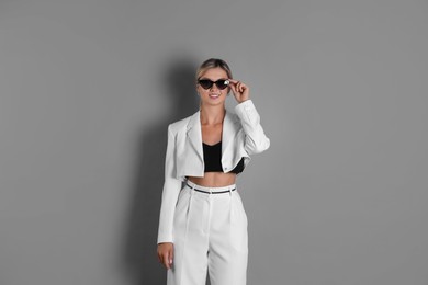 Photo of Beautiful woman in stylish white suit on grey background