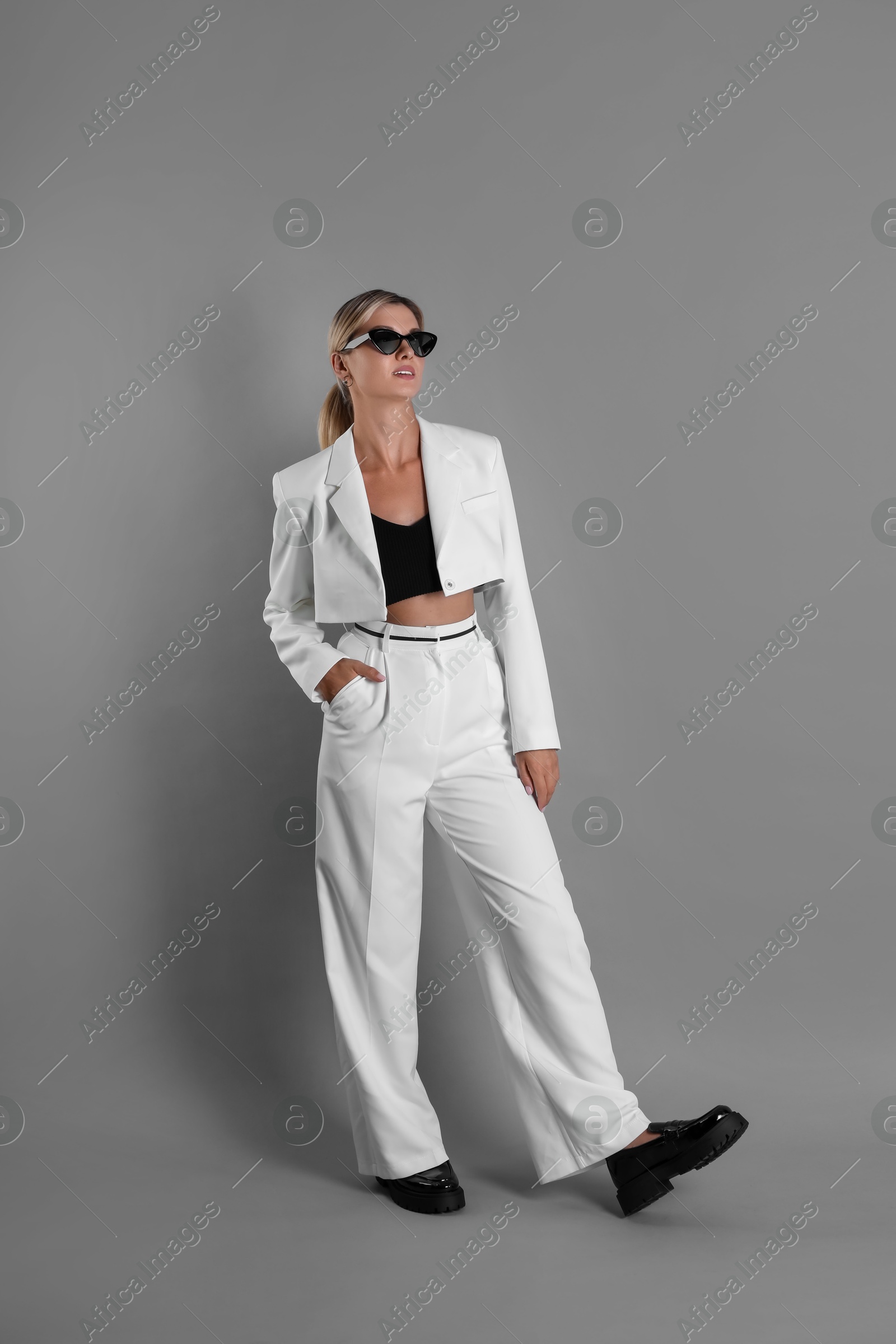 Photo of Beautiful woman in stylish white suit on grey background