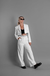 Photo of Beautiful woman in stylish white suit on grey background