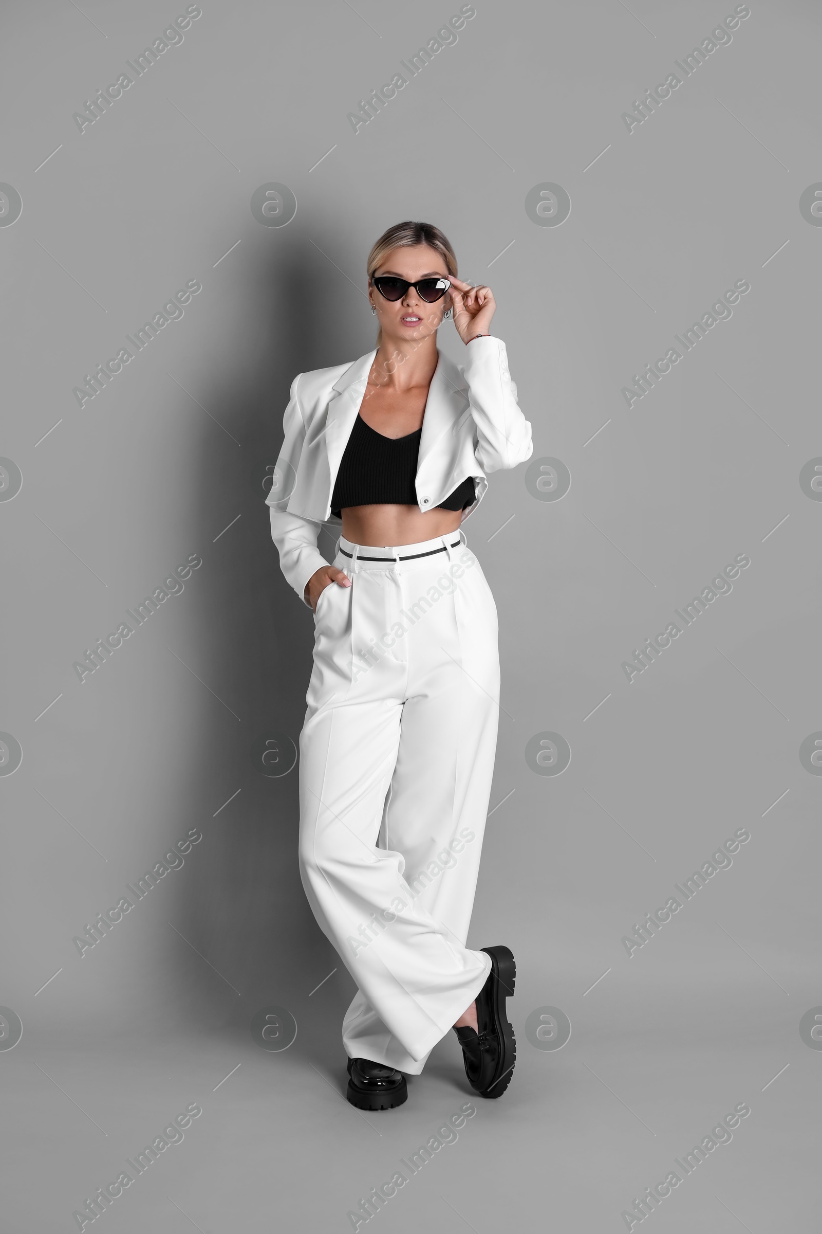 Photo of Beautiful woman in stylish white suit on grey background