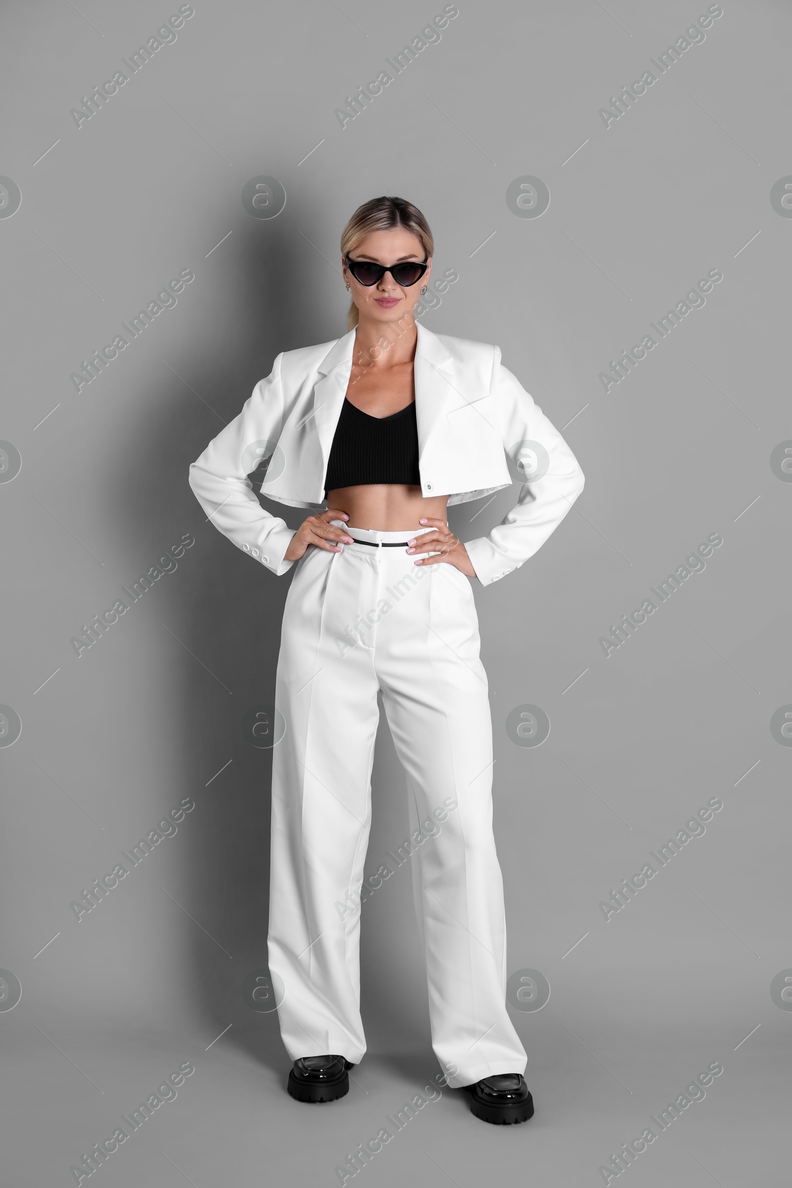 Photo of Beautiful woman in stylish white suit on grey background