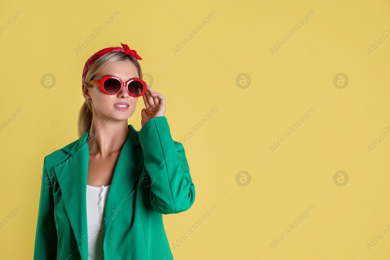 Photo of Beautiful woman in stylish green jacket on yellow background, space for text