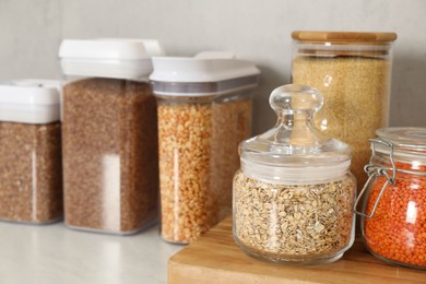 Photo of Different types of cereals and legumes in containers on light table