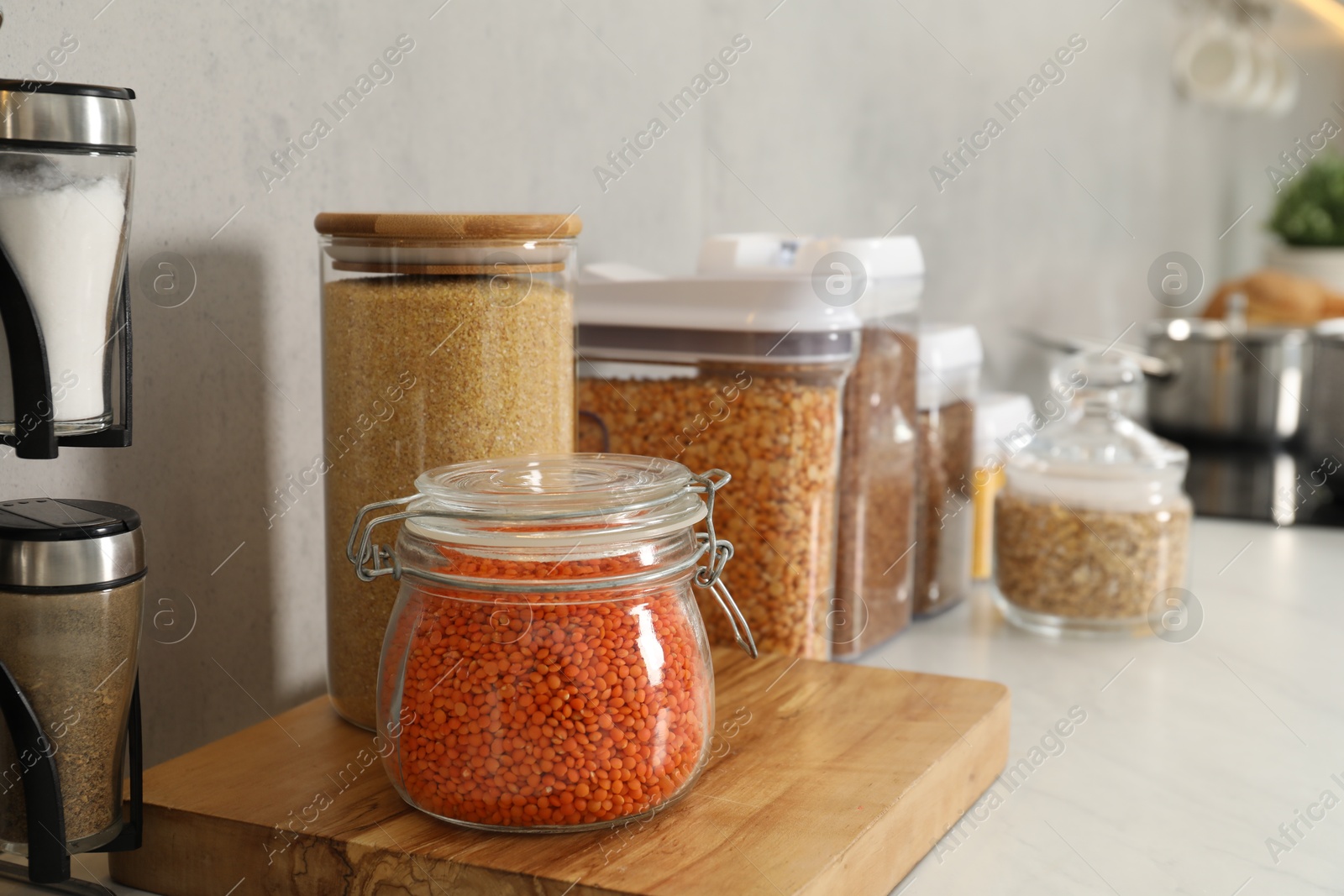 Photo of Different types of cereals and legumes in containers on light table