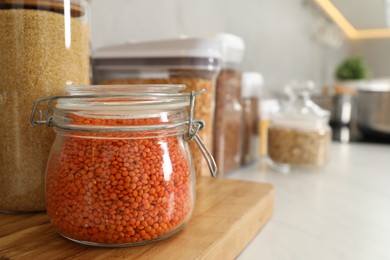 Photo of Different types of cereals and legumes in containers on light table in kitchen, closeup. Space for text