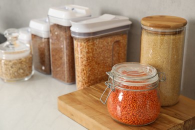 Photo of Different types of cereals and legumes in containers on light table