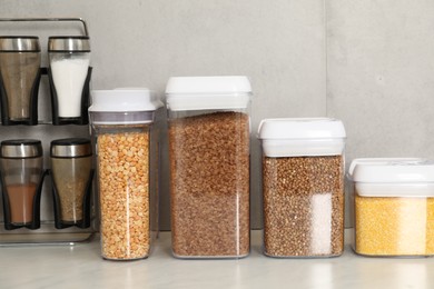 Photo of Different types of cereals and legumes in containers on light marble table