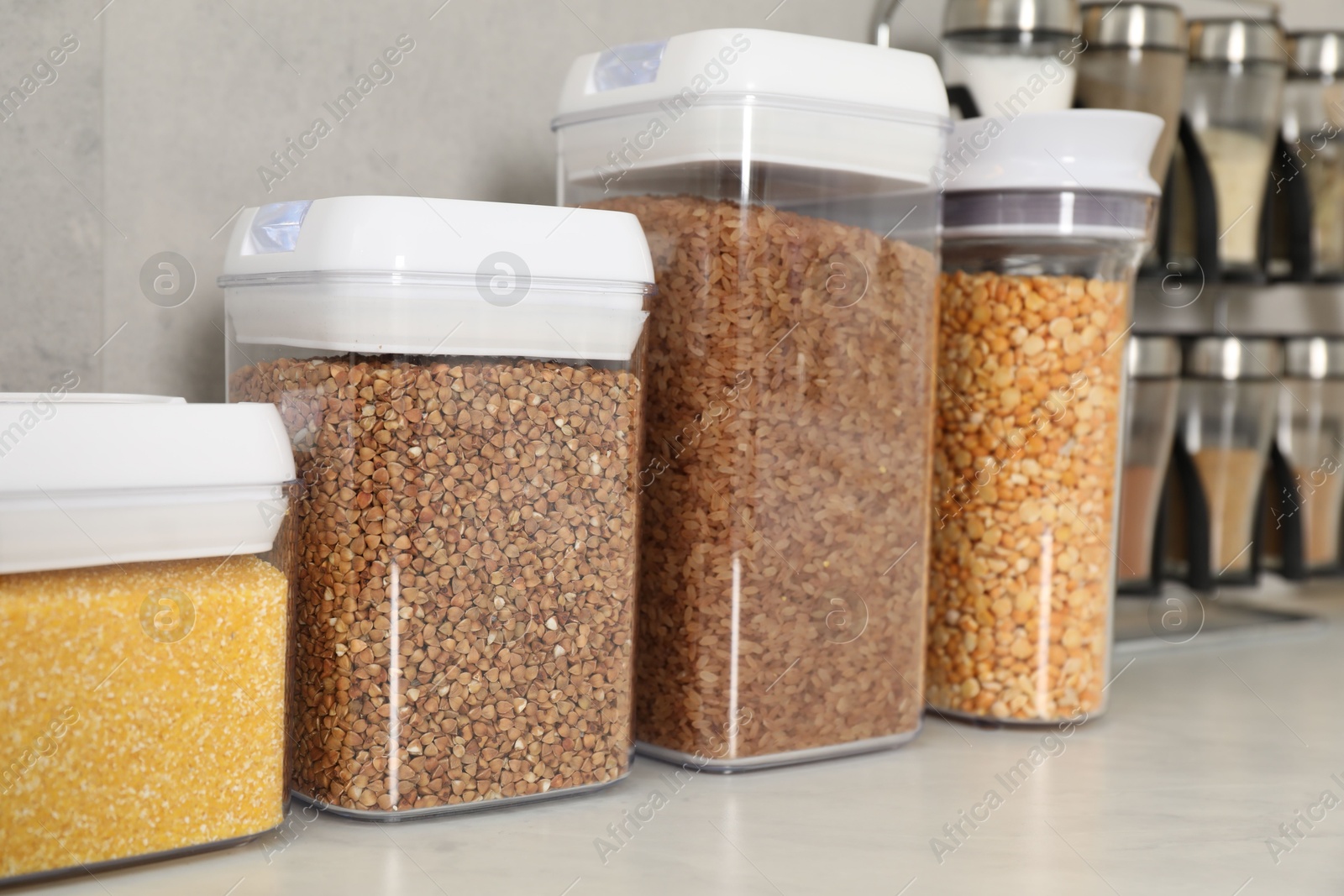 Photo of Different types of cereals and legumes in containers on light marble table, closeup