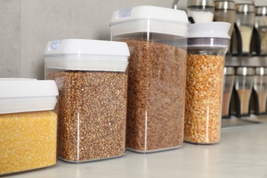 Photo of Different types of cereals and legumes in containers on light marble table, closeup