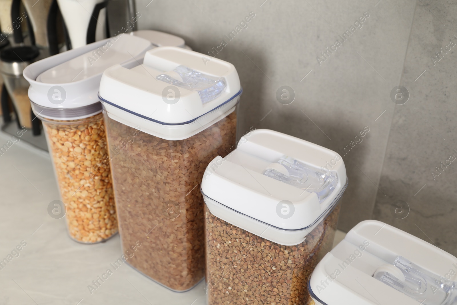 Photo of Different types of cereals and legumes in containers on light marble table