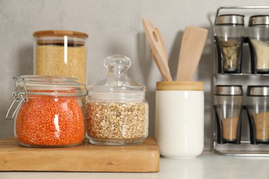 Photo of Different types of cereals and legumes in containers on light table