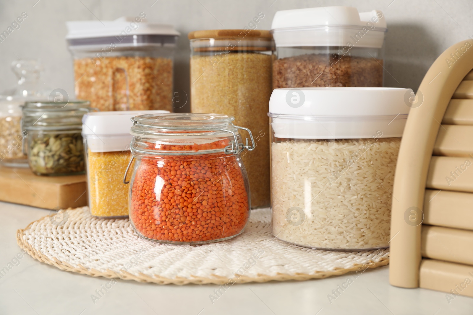 Photo of Different types of cereals and legumes in containers on light table