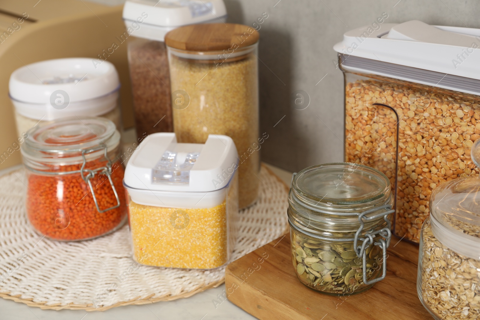 Photo of Different types of cereals, seeds and legumes in containers on light table