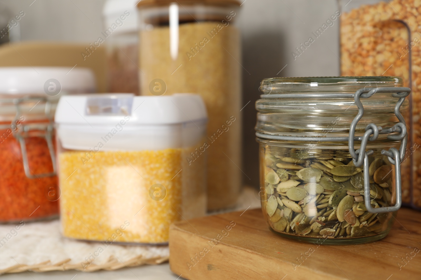 Photo of Different types of cereals, seeds and legumes in containers on light table, closeup