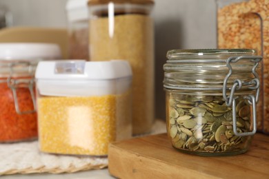 Photo of Different types of cereals, seeds and legumes in containers on light table, closeup