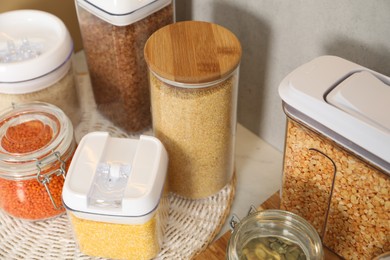 Photo of Different types of cereals and legumes in containers on light table